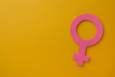 Female gender sign and space for text on orange background, top view. Women's health concept
