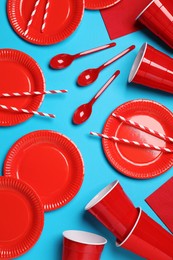 Photo of Disposable tableware on light blue background, flat lay