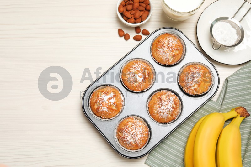 Photo of Flat lay composition with homemade banana muffins and milk on white wooden table. Space for text