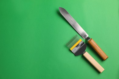 Photo of Uncapping fork and knife on green background, flat lay with space for text. Beekeeping tools