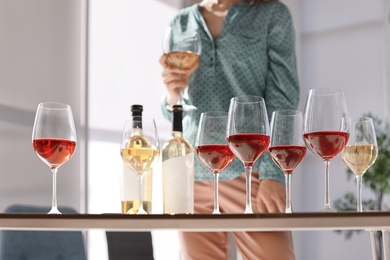 Glasses and bottles of wine and blurred woman on background