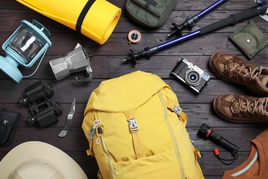 Flat lay composition with backpack and other camping equipment for tourism on wooden background