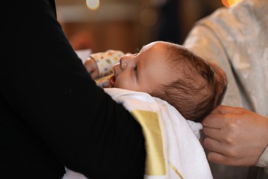 Man holding adorable baby in church during baptism ceremony, closeup