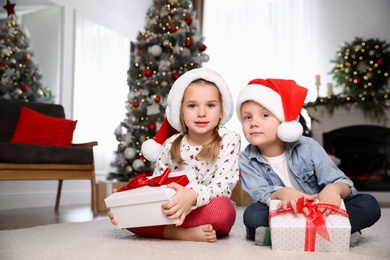 Cute little children with Christmas gifts on floor at home