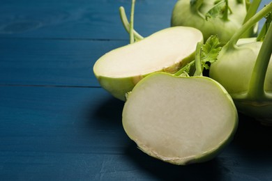 Whole and cut kohlrabi plants on blue wooden table
