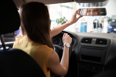 Young woman adjusting automobile rearview mirror