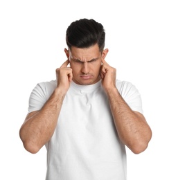 Emotional man covering ears with fingers on white background