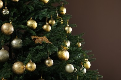 Beautifully decorated Christmas tree on brown background, closeup. Space for text