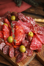 Photo of Tasty salami with other delicacies served on wooden table