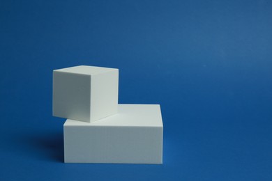 Photo of Product photography props. Podiums of different geometric shapes on blue background, space for text