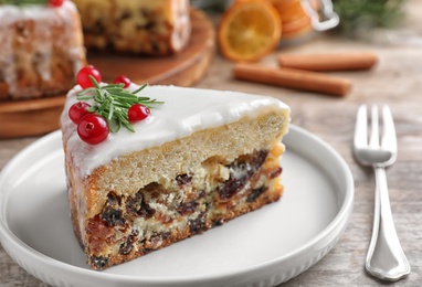 Slice of traditional Christmas cake decorated with rosemary and cranberries on table, closeup