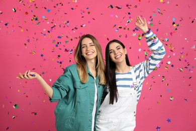 Happy women and falling confetti on pink background