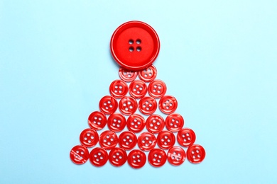 Christmas tree made with red buttons on light blue background, flat lay