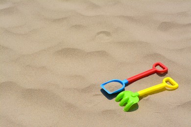 Photo of Plastic shovel and rake on sand, space for text. Beach toys