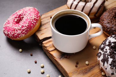 Photo of Yummy donuts with sprinkles and coffee on grey table