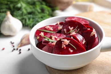 Raw beetroot slices, garlic and rosemary in bowl on white table, closeup