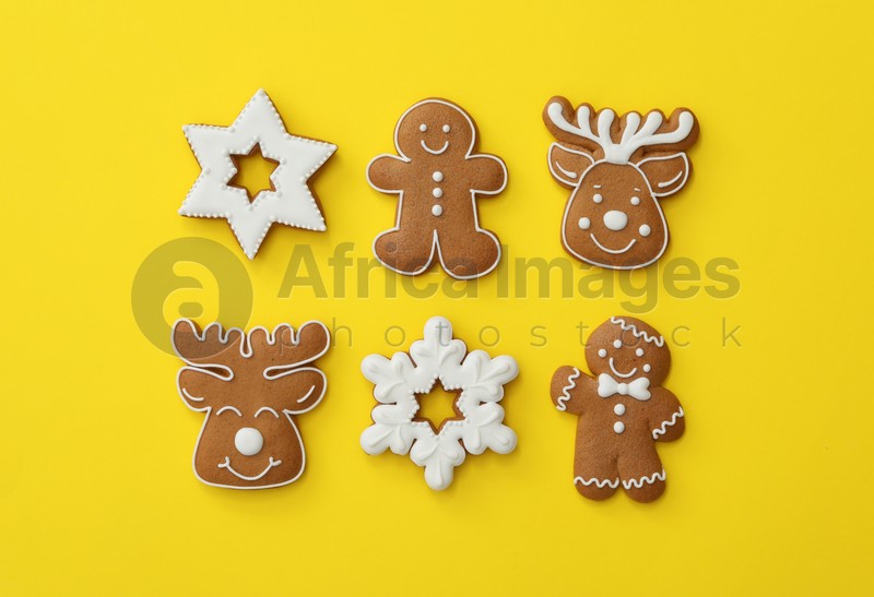 Different Christmas gingerbread cookies on yellow background, flat lay