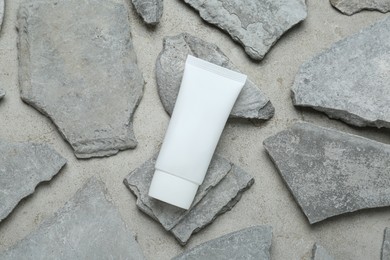 Photo of Flat lay composition with tube of hand cream and stones on grey background. Mockup for design