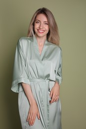 Pretty young woman in beautiful light green silk robe on olive background
