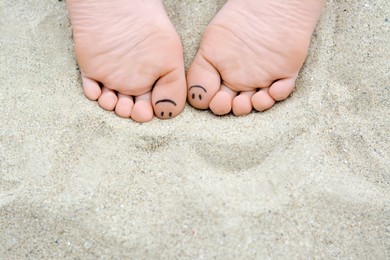 Photo of Woman with smiling faces drawn on toes, closeup of foot. Space for text
