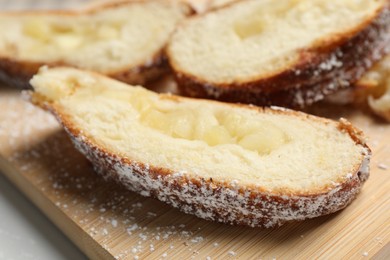 Photo of Pieces of delicious yeast dough cake on wooden board, closeup