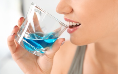 Woman rinsing mouth with mouthwash in bathroom, closeup.Teeth care