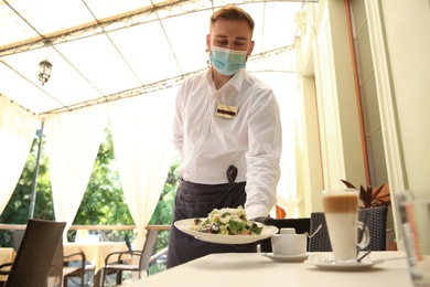 Waiter serving salad in restaurant. Catering during coronavirus quarantine