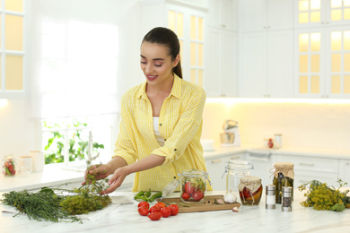 Woman preparing pickled vegetables at table in kitchen