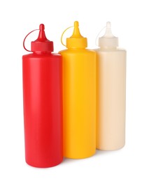 Plastic bottles of tasty mayonnaise, ketchup and mustard on white background