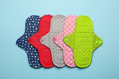 Many reusable cloth menstrual pads on light blue background, flat lay