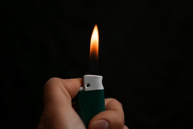 Woman holding lighter on black background, closeup