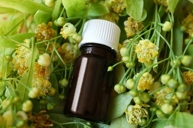 Bottle of essential oil on linden blossoms, above view