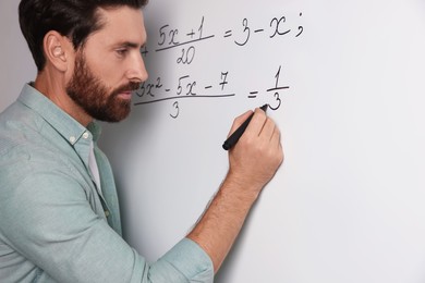 Photo of Mature teacher explaining mathematics at whiteboard in classroom, closeup