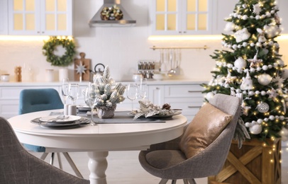 Table with set of dishware and beautiful Christmas decor in kitchen interior