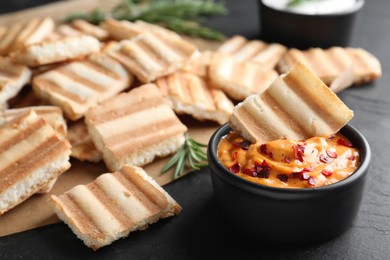 Photo of Delicious pita chips and sauce on black table, closeup