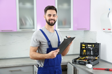 Male plumber with clipboard in kitchen. Repair service