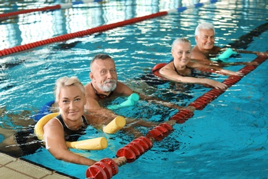 Sportive senior people doing exercises in indoor swimming pool