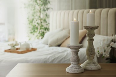 Pair of beautiful candlesticks on wooden table in bedroom, space for text