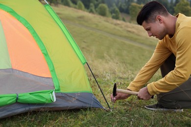 Man setting up camping tent on hill