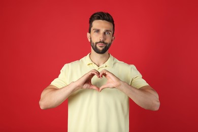 Man making heart with hands on red background
