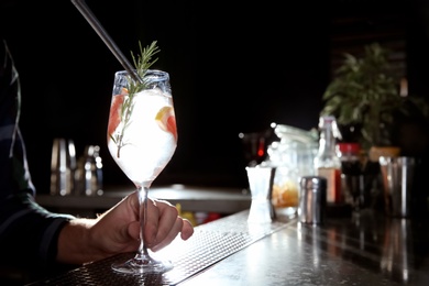 Barman making grapefruit gin tonic cocktail at counter in pub, closeup. Space for text