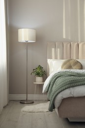 Photo of Stylish floor lamp and plant in bedroom. Interior element