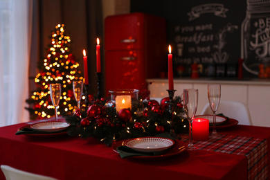 Table served for festive dinner and Christmas tree in stylish kitchen interior