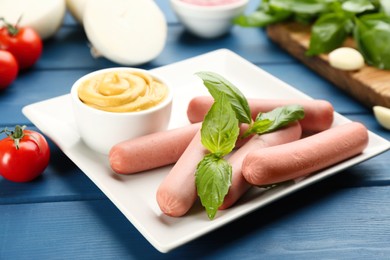 Fresh raw vegetarian sausages with basil and sauce on blue wooden table