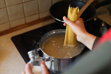Woman cooking spaghetti on stove in kitchen, closeup