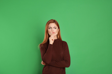 Pensive woman on green background. Thinking about answer for question