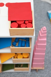 Set of wooden geometrical objects and other montessori toys on shelves indoors