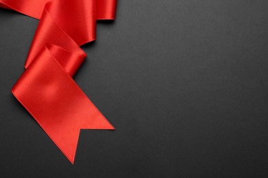 Beautiful red ribbon on black background, top view. Space for text