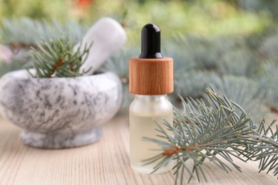 Pine essential oil and branches on white wooden table, closeup