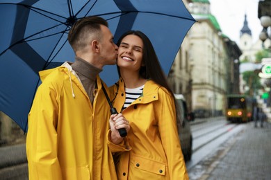 Photo of Lovely young couple with umbrella kissing under rain on city street
